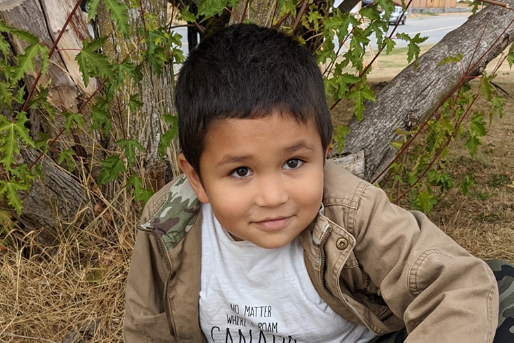 child sitting by a tree outside