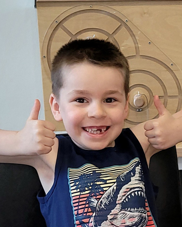 smiling child giving two thumbs up