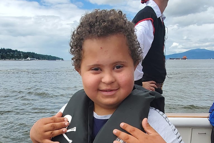 child wearing lifejacket standing by the water