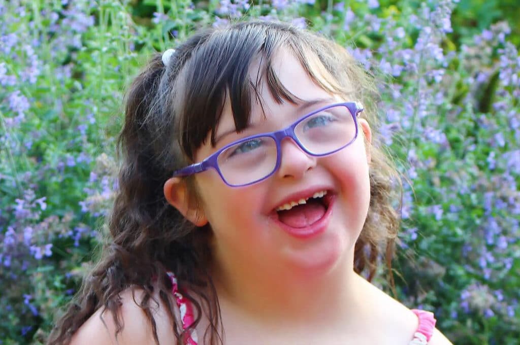 smiling child in a sun dress with lavender bushes behind