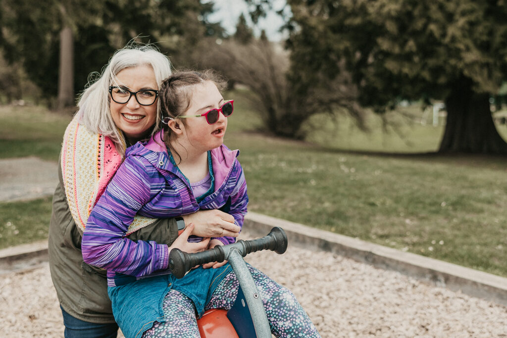 Mother and Daughter embracing and smiling outside at a playground