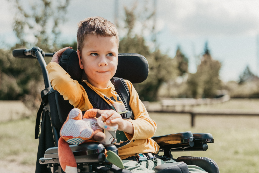 Davyd, who has cerebral palsy, poses in his adaptive chair in a park near his house.