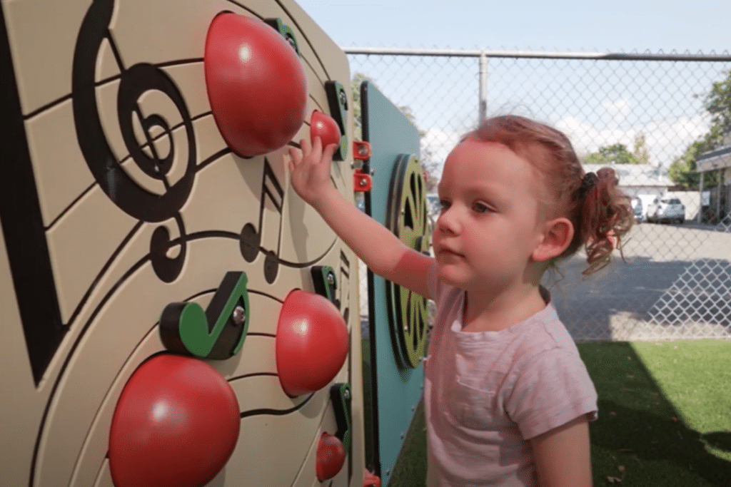 A little girl with pony tails plays in a park.