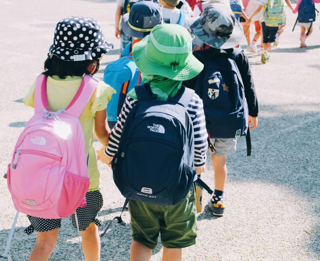 Children walking with backpacks outdoors.