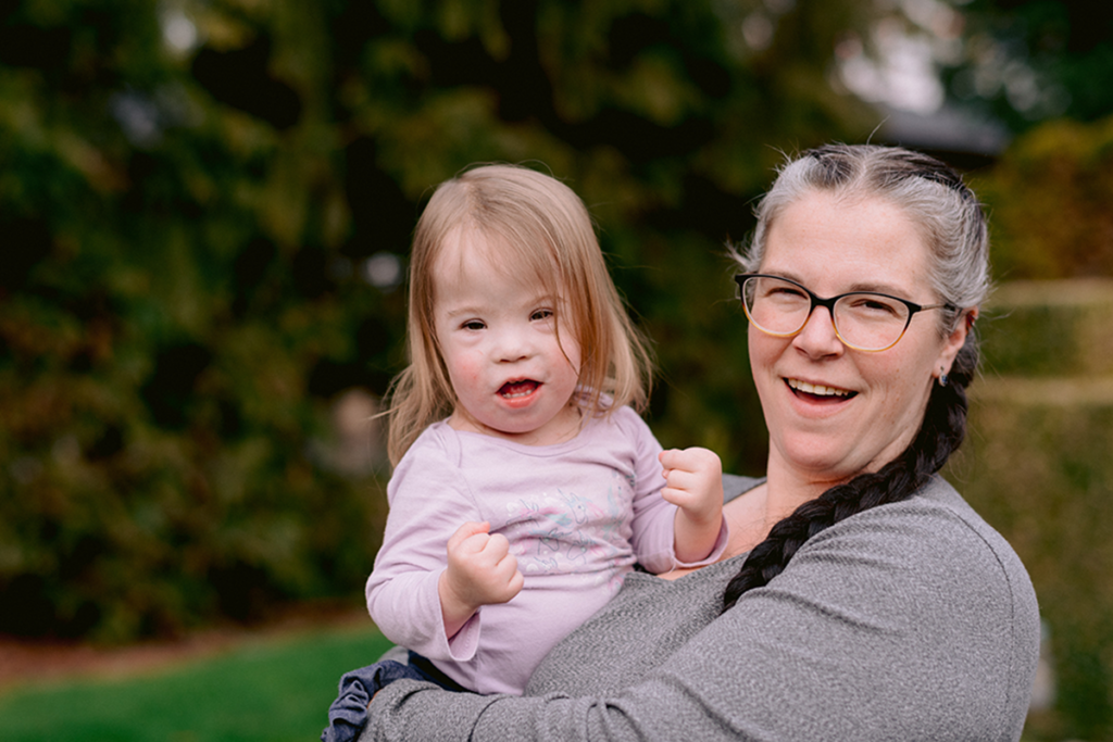 Mom carries her daughter outdoors.