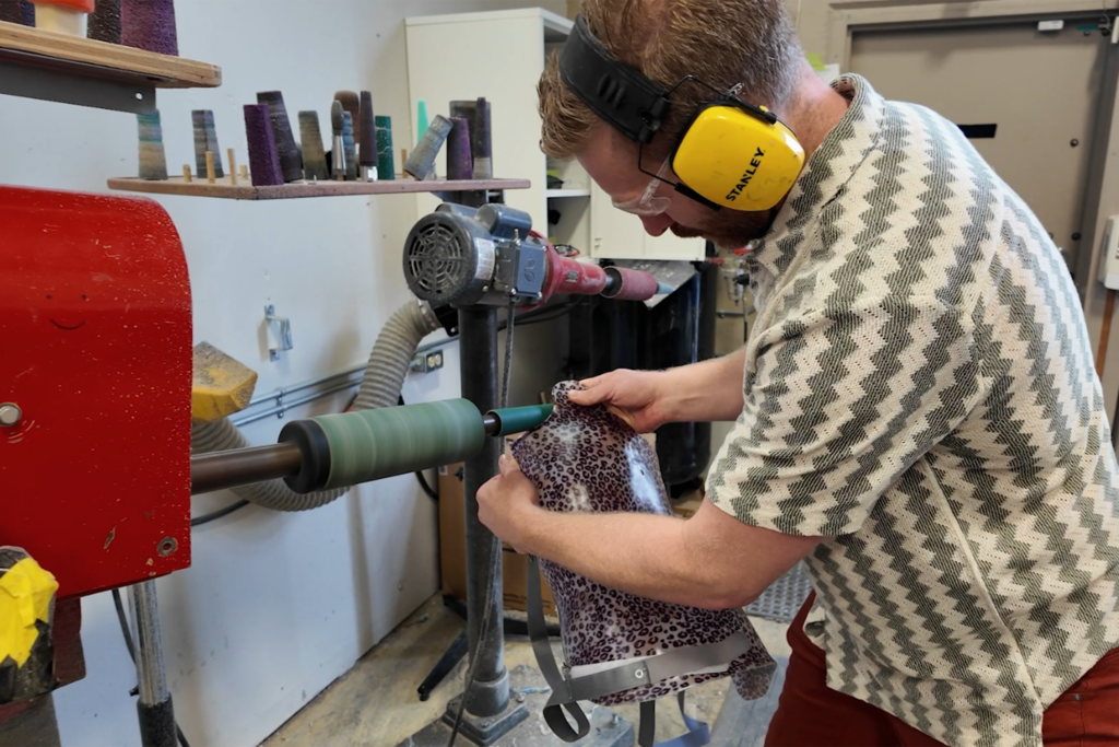 An orthotist wearing safety headphones makes adjustments to a back brace in his workshop.